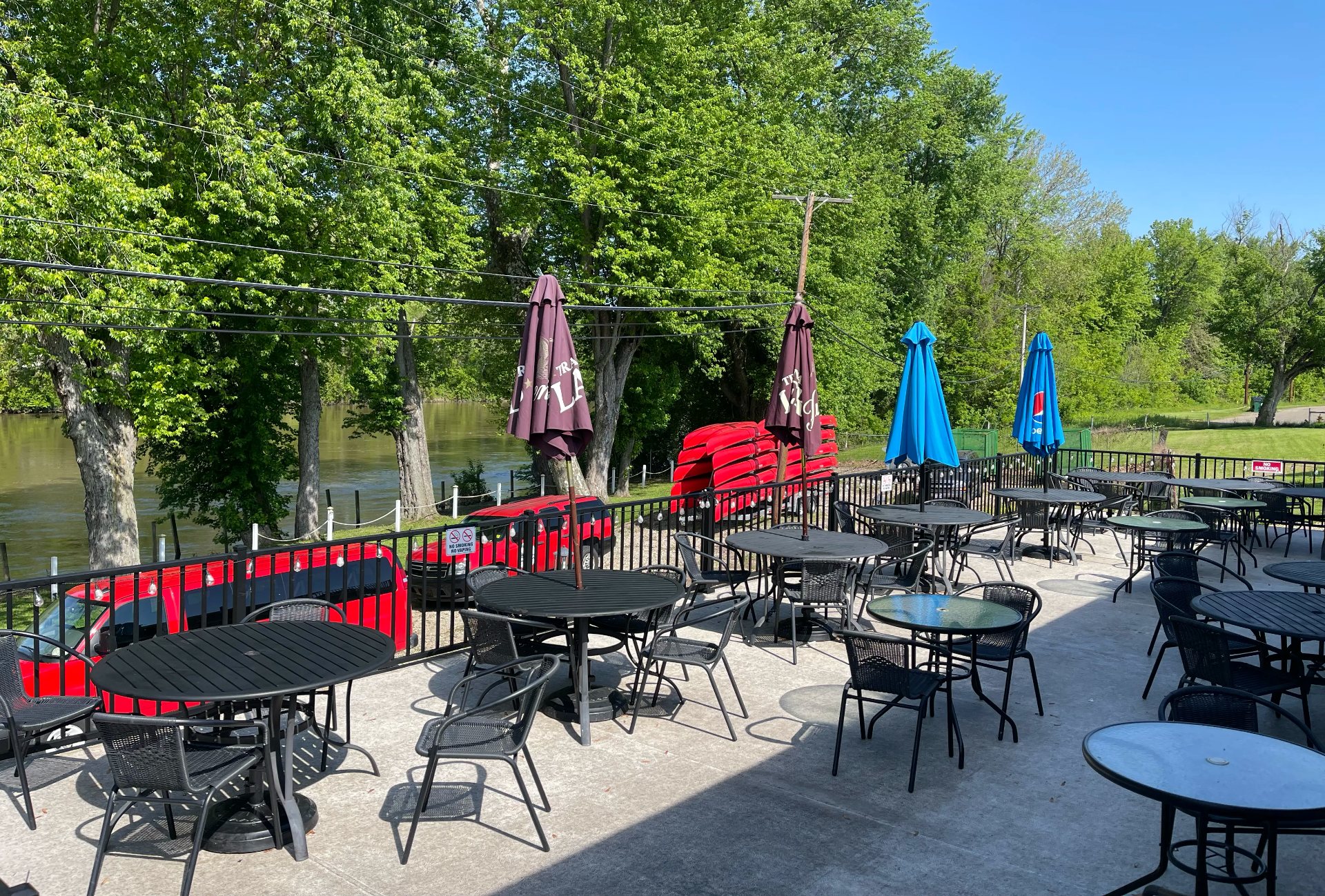 Shaded tables on the riverside patio at The Boathouse Tavern