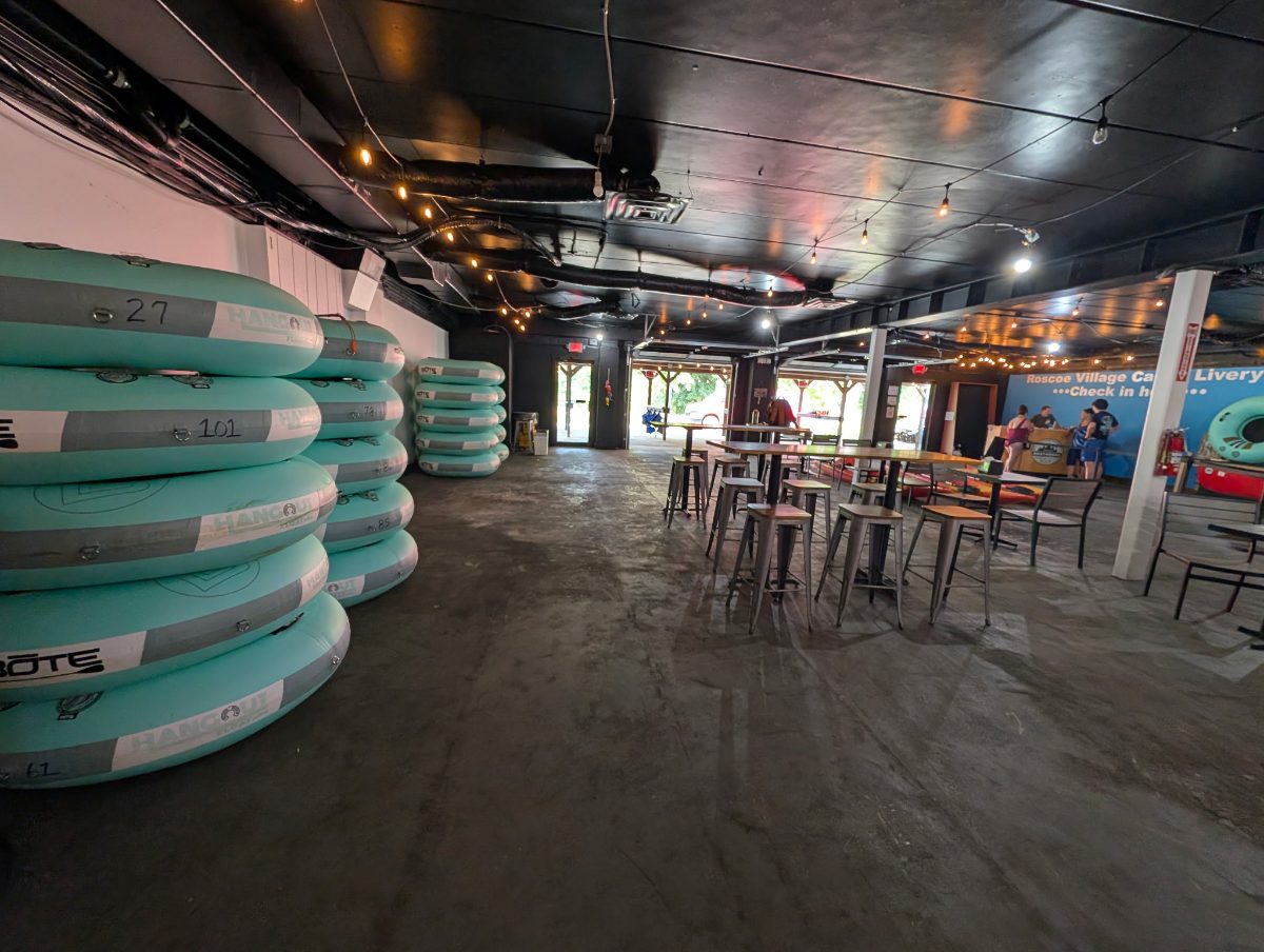 Stacked BOTE tubes and high-top tables beside the Roscoe Village Canoe Livery check-in counter