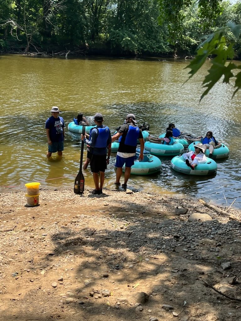 Livery staff launching a group of tubers from the gravel bank